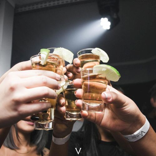 A group of people cheers with shot glasses, lime wedges, celebrating together. Top it at 140 characters, always ending the sentence.